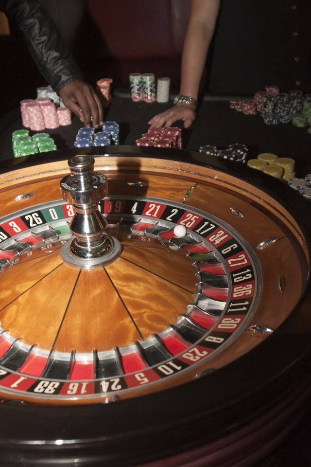 A roulette wheel with a dealer placing coloured chips on the table